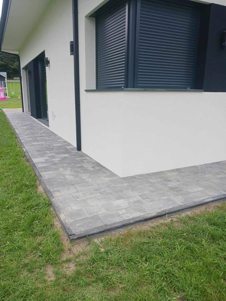 a white house with a black door and a grey walkway