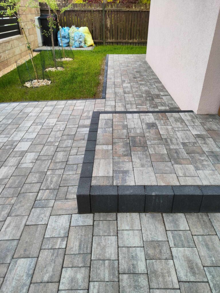 a brick patio with grass and a house